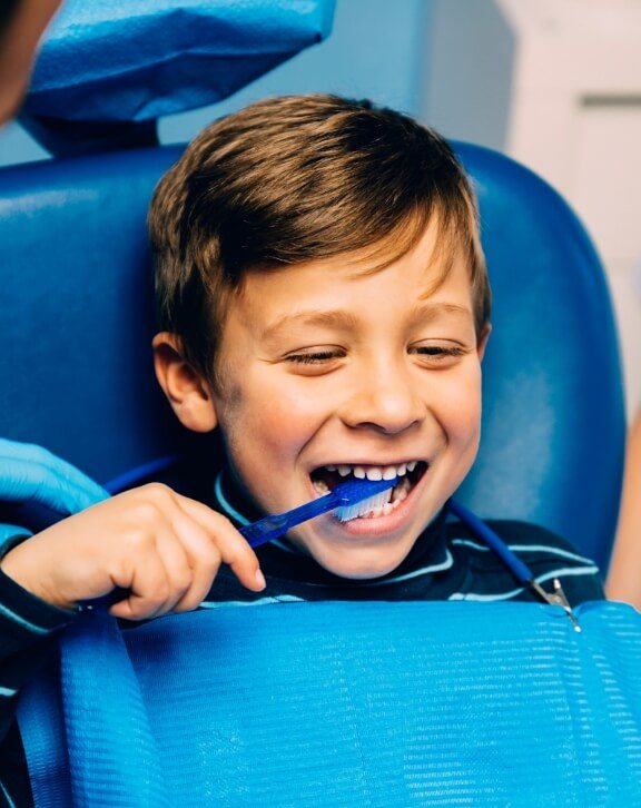 Smiling boy brushing his teeth in the dental chair while seeing childrens dentist in Rutland