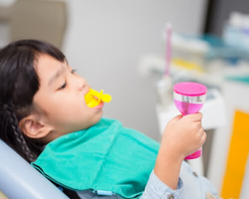 Young girl in dental chair with fluoride on her teeth