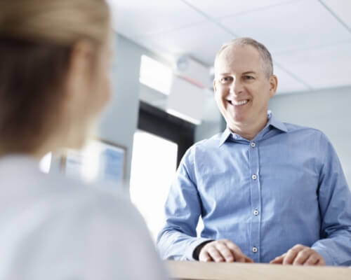 Man smiling at a dental office receptionist