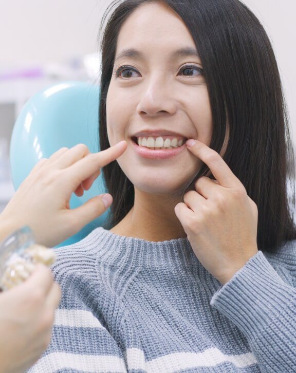 Dental patient pointing to her smile after gum disease treatment in Rutland