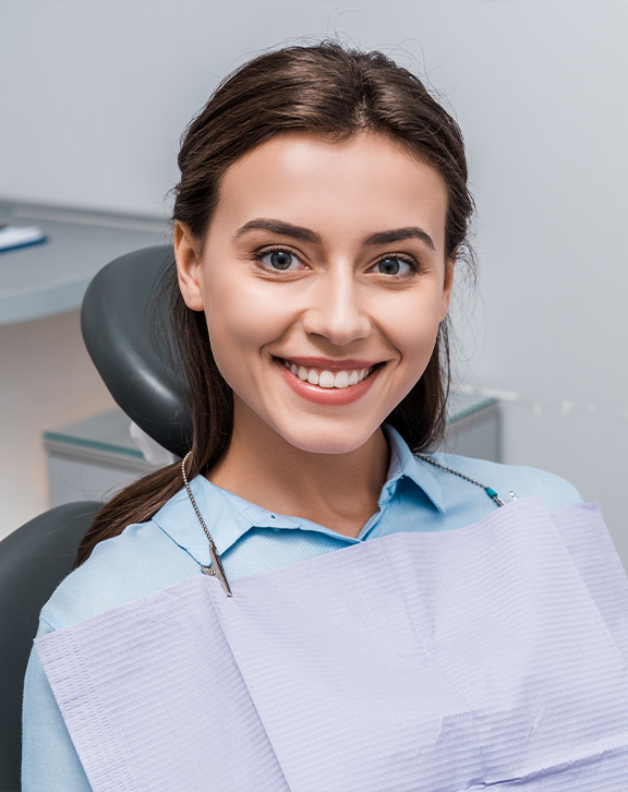 Smiling woman sitting in a dental chair during a preventive dentistry checkup