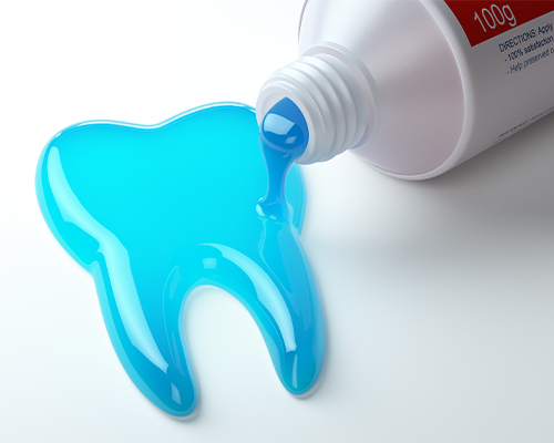 Blue toothpaste spilling out of a tube into the shape of a tooth