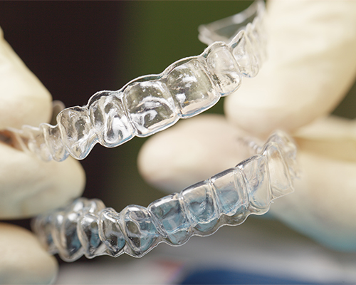 Gloved hands holding two clear nightguards